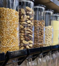 A close-up photo of gravity food dispensers containing various nuts.